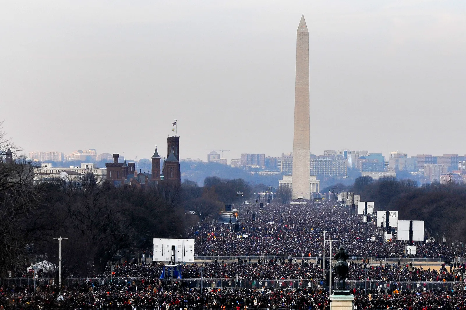 The National Mall packed with a vast crowd on Inauguration Day, the Washington Monument and Smithsonian Castle rising over the people, in Washington, D.C.